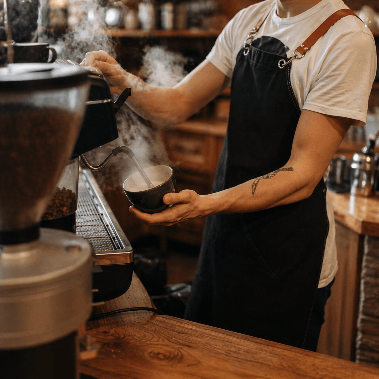 Barista vertiendo leche en taza de café